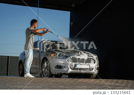 Foam is being washed, automobile is in soap. Man is with his car outdoors 133215681