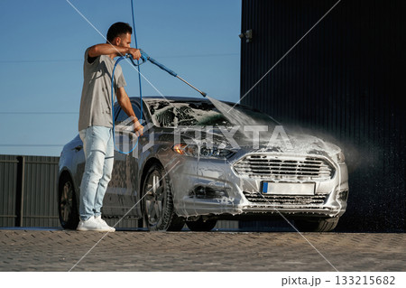 Foam is being washed, automobile is in soap. Man is with his car outdoors 133215682