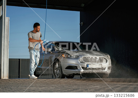 Water high pressure stream, car wash. Man is with his automobile outdoors 133215686
