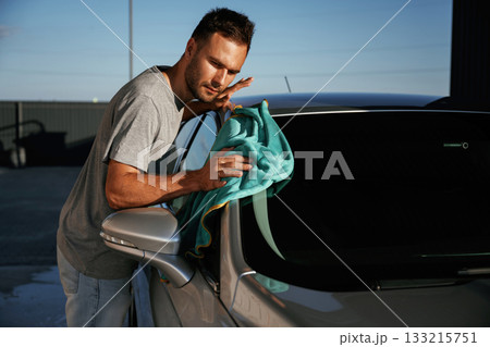 Turquoise cloth, polishing the vehicle. Man is with his car outdoors 133215751