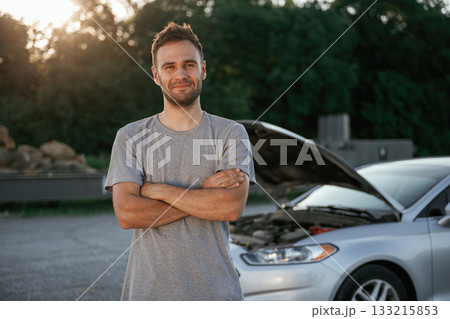 Arms crossed, standing. Man is with his car outdoors Arms crossed, standing. Man is with his car outdoors 133215853