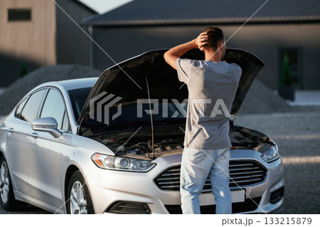 Issue, vehicle is broken. Man is with his car outdoors Issue, vehicle is broken. Man is with his car outdoors 133215879