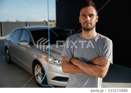 Arms crossed, standing. Man is with his car outdoors 133215886