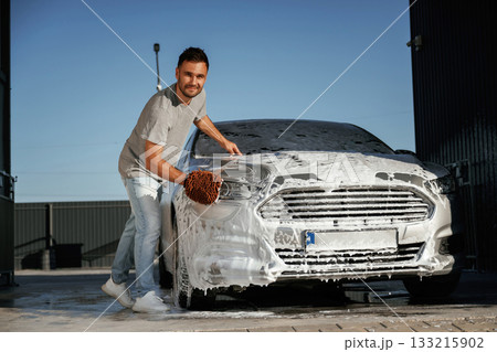 White cleaning chemical, washing the automobile. Man is with his car outdoors White cleaning chemical, washing the automobile. Man is with his car outdoors 133215902