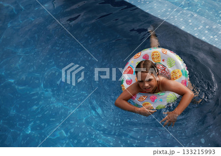 With lifebuoy, learning how to swim. Happy little girl is having fun in the pool 133215993