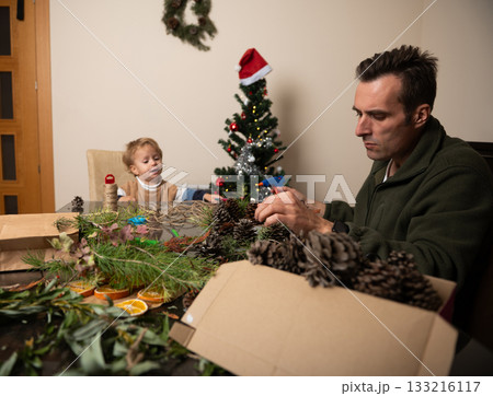 Family Christmas Crafting: Father And Child Create Decorations At Home By The Tree Family Christmas Crafting: Father And Child Create Decorations At Home By The Tree 133216117