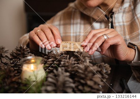 Hands Place A Merry Christmas Tag Among Pine Cones In Rustic Cozy Home Decor 133216144