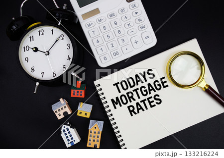 Notepad with the phrase "Todays Mortgage Rates" surrounded by a pen, calculator, magnifying glass, clock, and house model 133216224