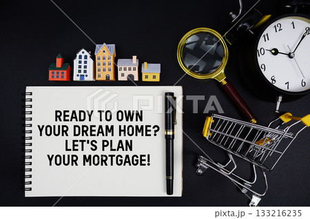 Notepad with the phrase "Ready to Own Your Dream Home? Let's Plan Your Mortgage!" surrounded by a pen, mini trolley shopping cart, magnifying glass, clock, and house model 133216235