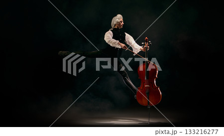 Dancer performing dramatic split leap while bowing cello with expressive control 133216277