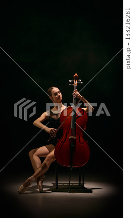 Dancer balancing cello in elegant pose with precision and emotional musical control. 133216281