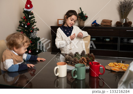 Family Christmas Craft Time With Pinecones and Cozy Home Decorations In A Warm Living Room Family Christmas Craft Time With Pinecones and Cozy Home Decorations In A Warm Living Room 133216284