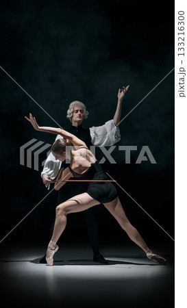 Expressive ballet duet with conductor refining dancer curved posture in dramatic light 133216300