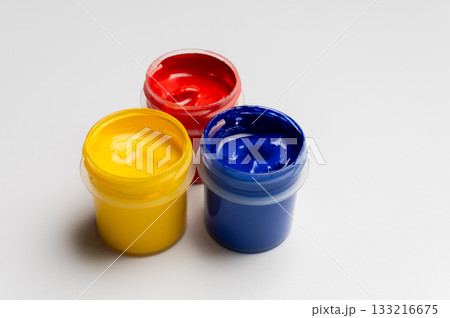 Jars of multi-colored gouache on a white background. Blue, red, and yellow traffic light colors. 133216675