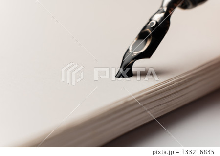 A close-up macro shot of a drop of ink on a notepad. A fountain pen is nearby. Retro office concept. A close-up macro shot of a drop of ink on a notepad. A fountain pen is nearby. Retro office concept. 133216835
