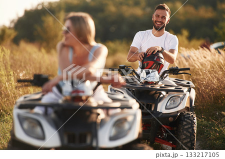Enjoying the ride, on the field. Man and woman are on ATV outdoors Enjoying the ride, on the field. Man and woman are on ATV outdoors 133217105