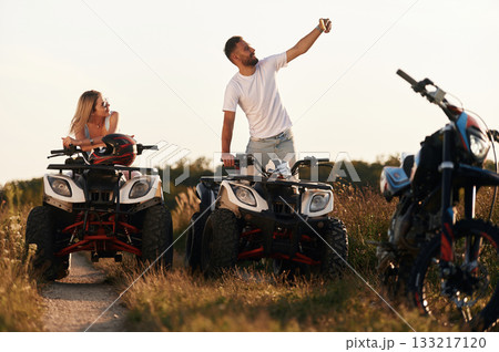 Making a selfie. Man and woman are on ATV outdoors Making a selfie. Man and woman are on ATV outdoors 133217120