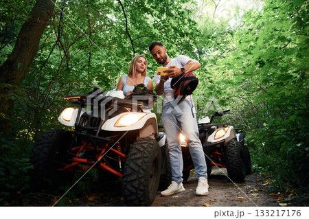 In safety helmets. Man and woman are on ATV outdoors 133217176