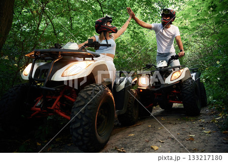 In the forest. Man and woman are on ATV outdoors 133217180