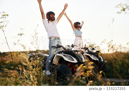 Hands raised up. Man and woman are on ATV outdoors 133217201
