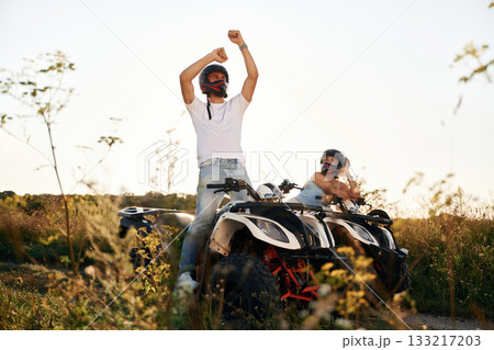 Hands raised up. Man and woman are on ATV outdoors Hands raised up. Man and woman are on ATV outdoors 133217203