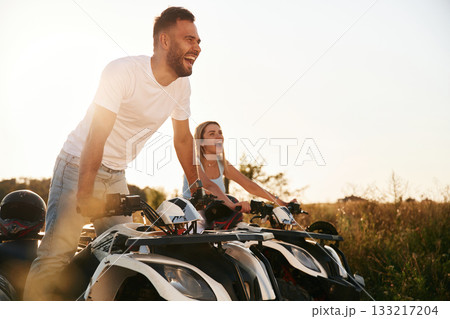 Under sunlight. Man and woman are on ATV outdoors 133217204