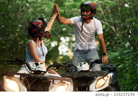 Green forest, adventure. Man and woman are on ATV outdoors 133217239