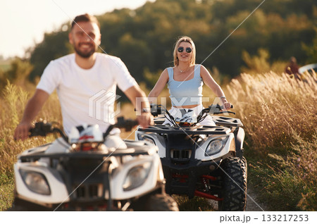 Cheerful facial expression. Man and woman are on ATV outdoors Cheerful facial expression. Man and woman are on ATV outdoors 133217253