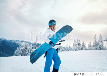 Portrait Of Woman On The Background Of Mountains. Holding a Snowboard And Wearing Ski Glasses Portrait Of Woman On The Background Of Mountains. Holding a Snowboard And Wearing Ski Glasses 133217302
