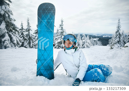 Young woman tourist helmet with snowboard on snow mountains background Young woman tourist helmet with snowboard on snow mountains background 133217309