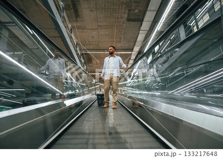 Front view. Handsome man is on the escalator in the mall 133217648