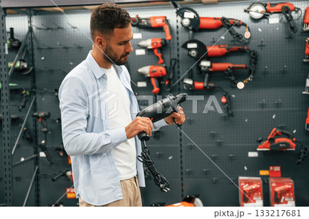 Checking the drill. Man is in the hardware shop 133217681