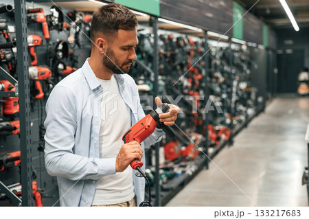 Checking the drill. Man is in the hardware shop Checking the drill. Man is in the hardware shop 133217683