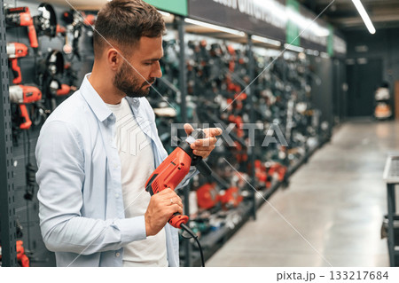 Checking the drill. Man is in the hardware shop Checking the drill. Man is in the hardware shop 133217684