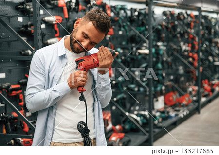 Checking the drill. Man is in the hardware shop 133217685