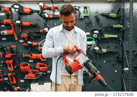 Plural perforator in hands. Man is in the hardware shop Plural perforator in hands. Man is in the hardware shop 133217686