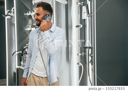 Talking by showerhead, having fun, joking. Man is in the hardware shop Talking by showerhead, having fun, joking. Man is in the hardware shop 133217833