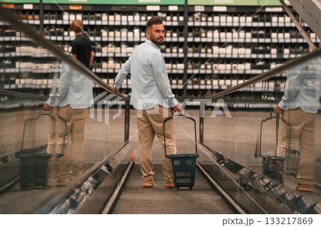 Customer is on the way. Handsome man is on the escalator in the mall Customer is on the way. Handsome man is on the escalator in the mall 133217869