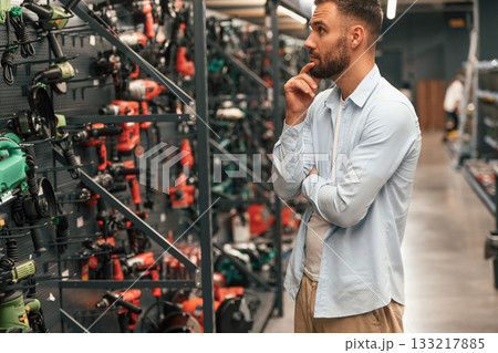 Wall with brand new drills. Man is in the hardware shop 133217885