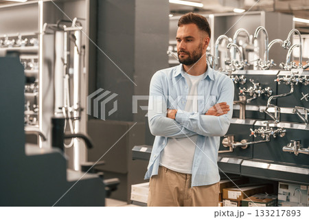 Standing with arms crossed, bathroom goods. Man is in the hardware shop 133217893
