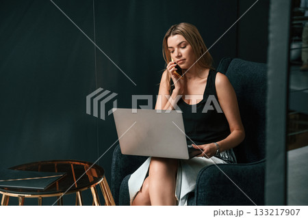 Woman is sitting and working by using the laptop Woman is sitting and working by using the laptop 133217907