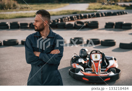 Standing with arms crossed. Man is outdoors, kart racing conception 133218484