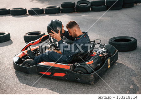 Wearing the safety helmet. Man is outdoors, kart racing conception Wearing the safety helmet. Man is outdoors, kart racing conception 133218514
