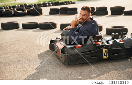 Looks behind while riding. Man is outdoors, kart racing conception 133218519