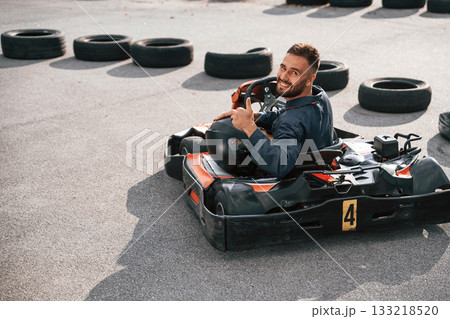 Riding and looking behind. Man is outdoors, kart racing conception Riding and looking behind. Man is outdoors, kart racing conception 133218520