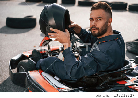 Riding and looking behind. Man is outdoors, kart racing conception Riding and looking behind. Man is outdoors, kart racing conception 133218527