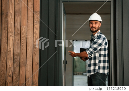 Showing the wooden house that is under construction. Industrial worker in warehouse Showing the wooden house that is under construction. Industrial worker in warehouse 133218920