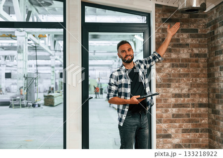 Showing the wooden house that is under construction. Industrial worker in warehouse Showing the wooden house that is under construction. Industrial worker in warehouse 133218922