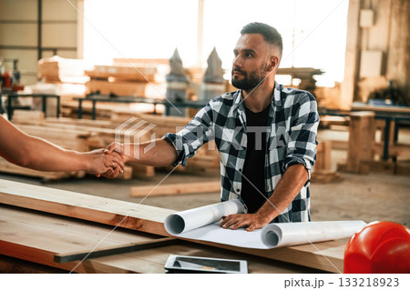 Having a deal, handshake. Two workers are in the industrial wooden warehouse Having a deal, handshake. Two workers are in the industrial wooden warehouse 133218923