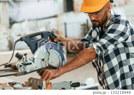 Using the saw to cut the wood. Industrial worker in warehouse Using the saw to cut the wood. Industrial worker in warehouse 133218949